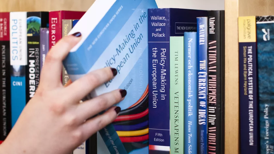 A hand pulling a book out of a bookshelf (image)