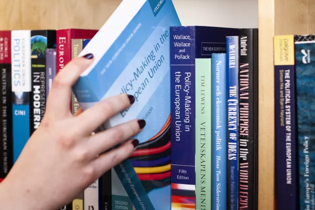 A hand pulling a book out of a bookshelf (image)