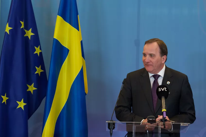 Statsminister Löfven och flaggor. Foto.